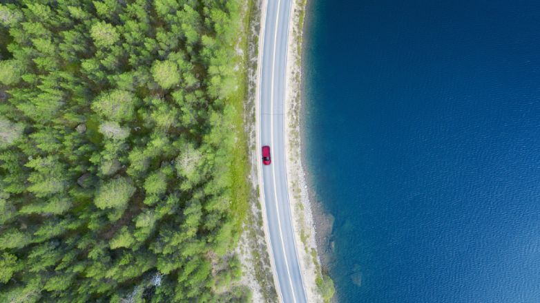 Car on a road between forest and water